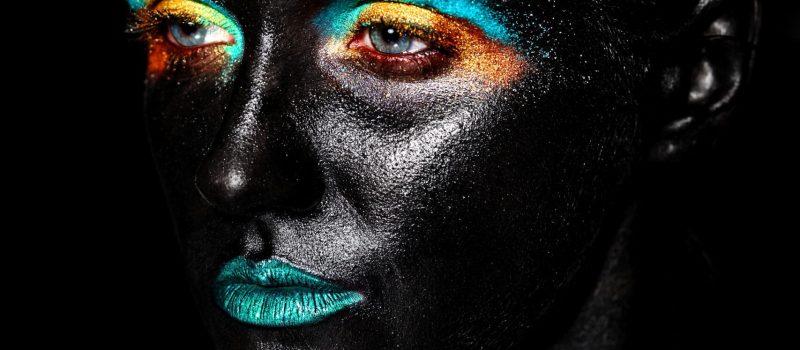 art photo of beautiful model woman with creative plastic unusual black mask bright colorful makeup with black face